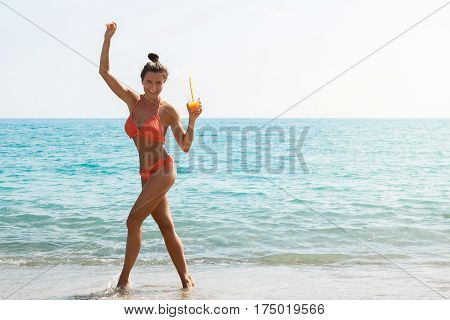 Beautiful woman on the beach with a glass of cocktail