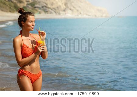 Beautiful woman on the beach with a glass of cocktail