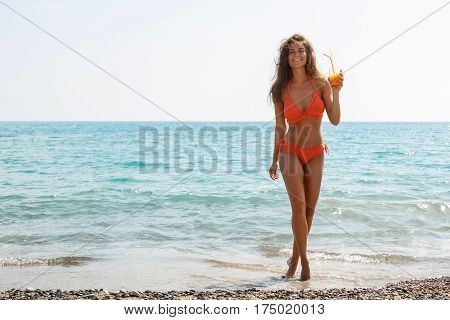 Beautiful woman on the beach with a glass of cocktail