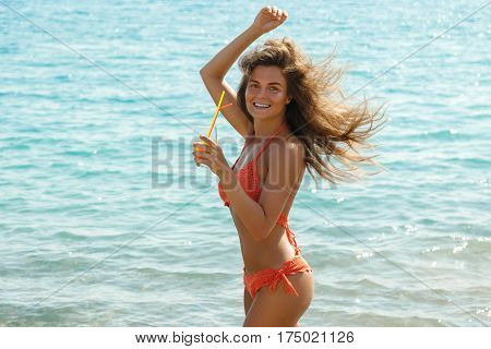 Beautiful woman on the beach with a glass of cocktail