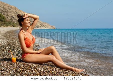 Beautiful woman on the beach with a glass of cocktail
