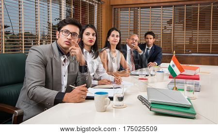 Group Of Indian Businesspeople In Video Conference or at presentation or listening to a sales speech At Business Meeting, with a miniature indian flag post over table