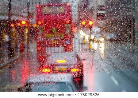 London rain view to red bus through rain-specked window