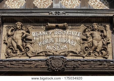 A close-up of the sculptured plaque on the facade of The Beaney House of Art and Knowledge in Canterbury England.