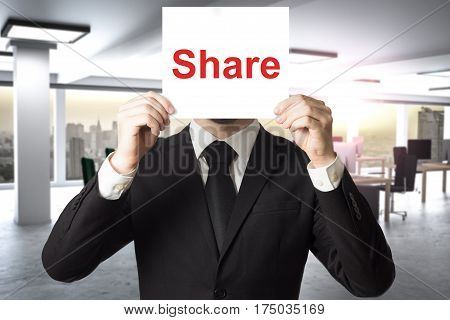 businessman in office hiding face behind sign share