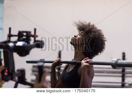 Young Cute african american sport woman in fitness room lifting empty bar