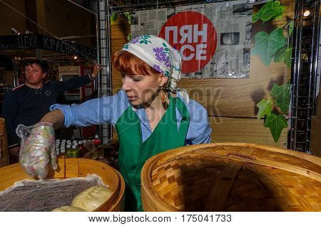Moscow, Russia - February 25, 2017: Red-haired woman prepares national Korean fast food pyan-se in a traditional bamboo steamer