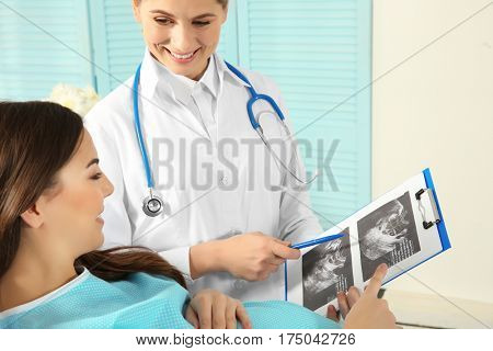 Doctor showing baby ultrasound image to pregnant woman