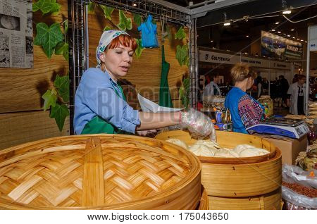 Moscow, Russia - February 25, 2017: Red-haired woman prepares national Korean fast food pyan-se in a traditional bamboo steamer