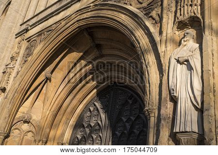 A sculpture of St. Benedict on the exterior of the West Porch of Norwich Cathedral in the historic city of Norwich UK.