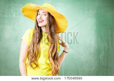 Colorful portrait of a beautiful woman in yellow t-shirt and hat on the green background