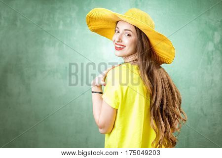 Colorful portrait of a beautiful woman in yellow t-shirt and hat on the green background