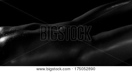 Low key photo of sexy nude female stomach with oil shiny skin. Selective focus