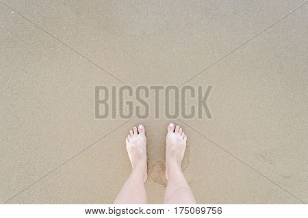 Beautiful female bare feet with pastel pedicure on the beach in sunny day. Summertime holidays concept. Top view. Copy space.