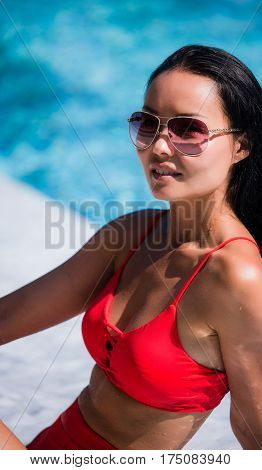 Close up lifestyle portrait of Cute girl swimming in pool, traveling and enjoy her summer vacation, perfect skin, trendy sunglasses. Outdoors lifestyle portrait