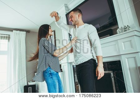 Portrait of beautiful romantic young smiling laughing couple man woman in love hugging kissing dancing together indoors at home in room toned with filters authentic candid lifestyle