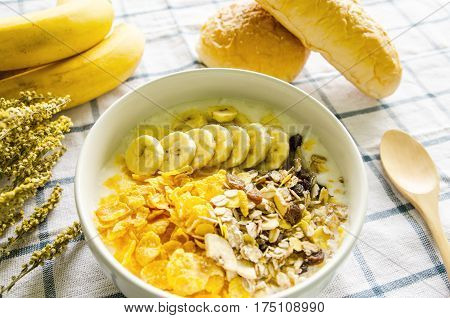 Yoghurt homemade with muesli and banana on wooden table.