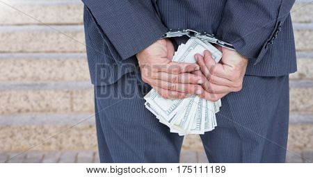 Businessman hands in handcuffs holding US dollars against blurr background