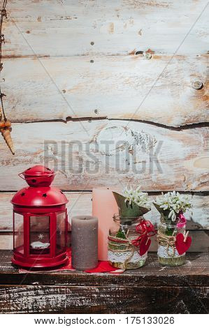 old wooden backgroud with candlestick candles and snowdrops