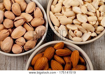Pistachios almonds peanuts in ceramic plates. On the wooden table. Healthy eating