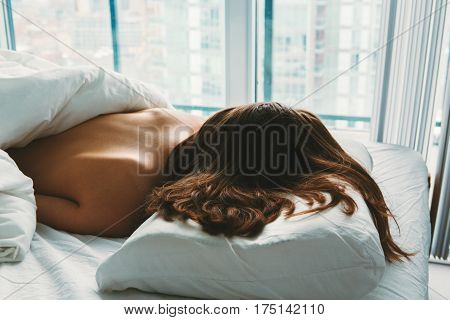 Portrait of young white Caucasian woman lying in bed sleeping her messy hair on pillow indoors at home early morning lifestyle toned with filters view from top above