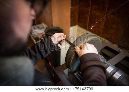 Close up shot of a man's hands sharpening a scissors.