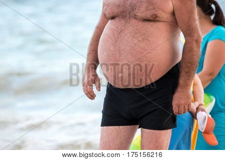 Guy with a big belly. Fat male outdoors. Change lifestyle to return health. High risk of hernia development.