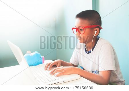 Little boy child wearing red glasses listening and using laptop computer
