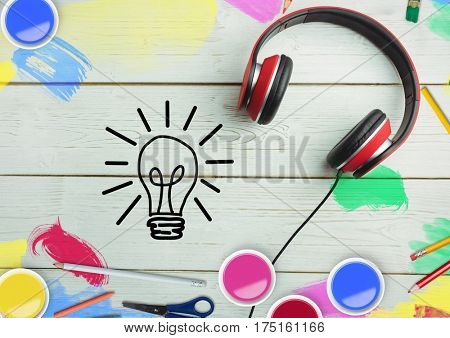 Digital composite image of headphone and light blub icon on wooden table