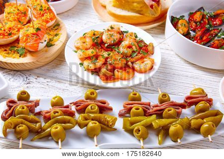 Tapas mix and pinchos food from Spain recipes also pintxos on a white wood board