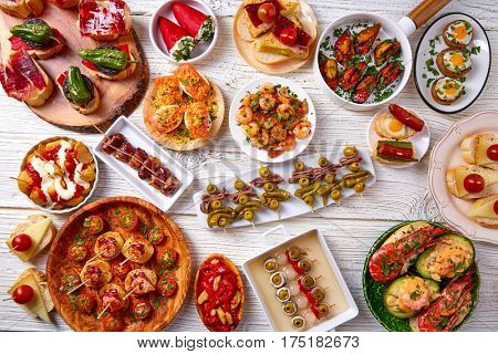 Tapas mix and pinchos food from Spain recipes also pintxos on a white wood board
