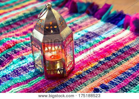 pink candle on a colorful handmade fabric .