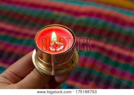 pink candle on a colorful handmade fabric .