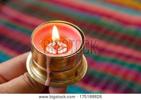 pink candle on a colorful handmade fabric .