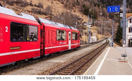 Filisur, Switzerland - 3 March, 2017: a train of the Rhaetian Railway heading to the town of St. Moritz leaving the Filisur railway station. The Rhaetian Railway (Italian: Ferrovia Retica), is a Swiss transport company.
