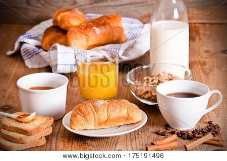 Breakfast with croissants with orange juice on wooden table.