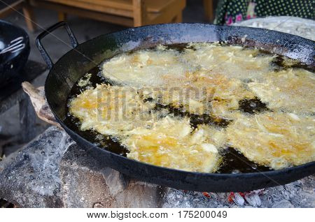 Deep fried shrimp in the black pan with hot oil inside. Cooking with old style.