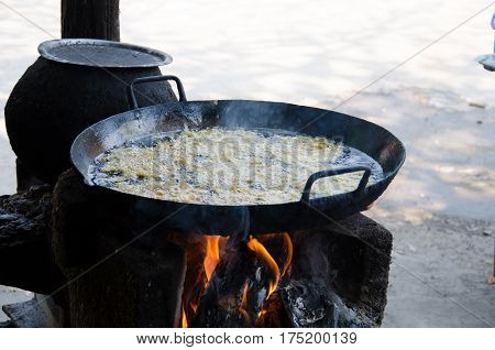 Deep fried shrimp in the black pan with hot oil inside. Cooking with old style.