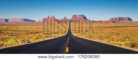 Classic panorama view of historic U.S. Route 163 running through famous Monument Valley in beautiful golden evening light at sunset on a beautiful sunny day with blue sky in summer Utah USA