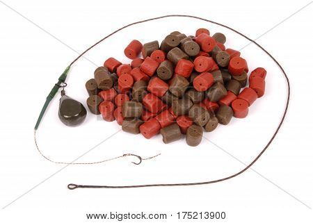 Fishing bait with hook and brown with red pre-drilled halibut pellets for carp fishing isolated on white background with soft shadow