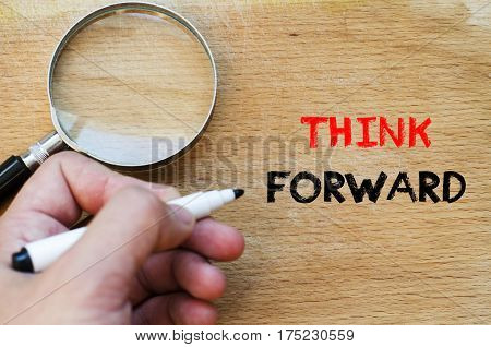 Human hand over wooden background and think forward text concept