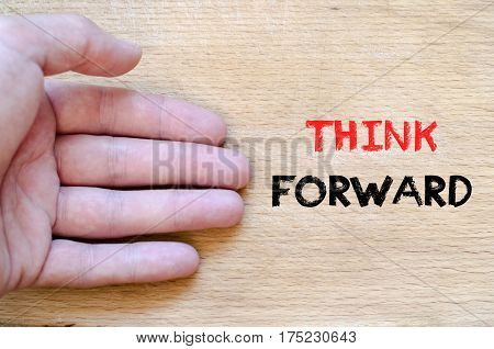Human hand over wooden background and think forward text concept