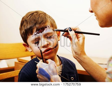 little cute child making facepaint on birthday party, zombie Apocalypse facepainting, halloween preparing concept at home