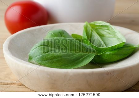 Fresh Basil Leaves In Bowl With Tomato In Background