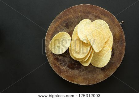 Pile of potato chips on wooden cutting board