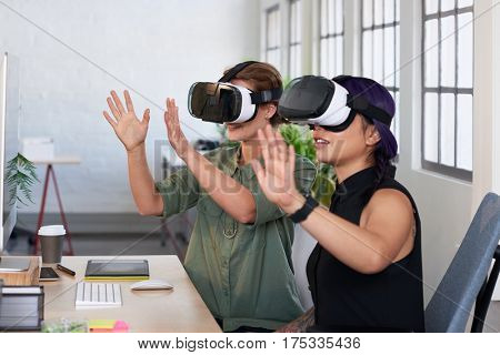 Asian woman showing her colleague her new project using virtual reality headsets, modern innovative architecture firm