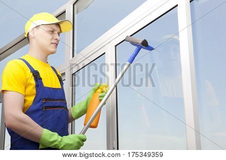 Professional cleaning. Young man washes window