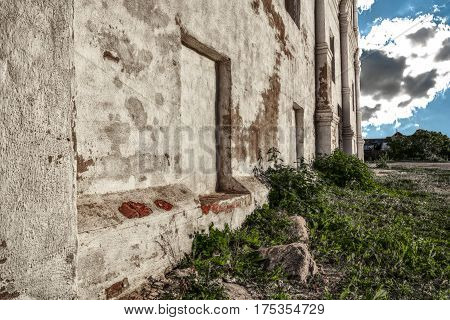 the nettle and grass grow at the immured windows in an old brick wall of Christian church