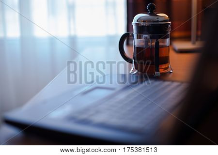 French press on the table. Computer on the table.