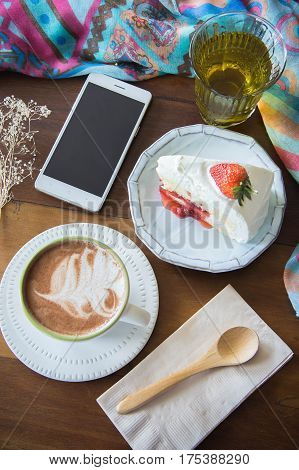 coffee cup and delicious cake strawberry and relax time moblie on table in coffee shop